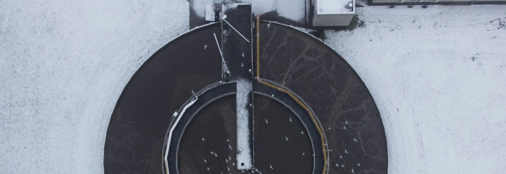 Bassin circulaire d’une station d’épuration vu du ciel, sous la neige