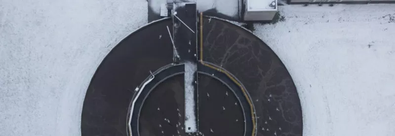 Bassin circulaire d’une station d’épuration vu du ciel, sous la neige